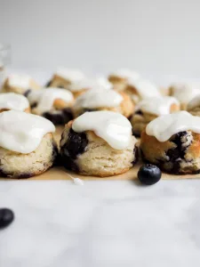 Blueberry Cream Cheese Biscuits recipe by Wood and Spoon. These are soft and fluffy southern style biscuits filled with butter and cream cheese. The glaze is a creamy frosting and the icing add sweetness to the pastry. These are great treats with fresh blueberries for weekday breakfast or weekend brunch. inspired by Callie's hot little biscuits, this food feels special and makes the mornings more fun. Find the recipe and how-to at thewoodandspoon.com by Kate Wood.