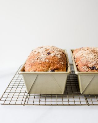 Blueberry Brioche recipe by Wood and Spoon blog. This is a recipe for two yeast loaves of brioche made with butter, egg, and a smidge of sugar. The fluffy white bread is studded with blueberries and seasoned with cinnamon. Each loaf has an optional crumble topping for extra sweet and salty in each bite. Learn how to fold and create this beautiful homemade breakfast treat here at thewoodandspoon.com by Kate Wood.