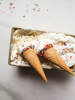 No-Churn Sugar Cookie Ice Cream Recipe. This is a simple frozen treat made with whipped cream and sweetened condensed milk. Clear vanilla flavors this birthday cake ice cream and there are chunks of eggless sprinkle sugar cookie dough. This Ice cream tastes like confetti cookie dough! So yummy, fun for kids and parties, and simple to make- no ice cream machine required! Find the recipe and how to on thewoodandspoon.com by Kate wood.